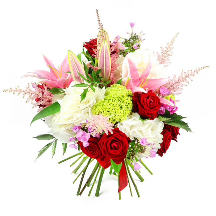 Photographed on a clean white background, this abundant hand-tied bouquet feels like a carefully composed snapshot of a sophisticated Grove Park celebration. At its heart, luxurious deep red roses bloom with velvety petals, their tightly layered spirals exuding warmth, passion, and timeless romance. Embracing them are graceful pink lilies, some fully open into broad, star-like flowers that reveal their stamens, others held in tall buds tipped with soft green and blush pink, suggesting a bouquet that will continue to unfold over several days. Cushioning these prominent blooms, generous clusters of white flowers - likely hydrangeas or ruffled carnations - create a soft, cloud-like base, adding both volume and a serene brightness. Near the centre, a distinct orb of lime green dianthus provides a modern focal point; its finely fringed texture resembles a small mossy cushion and injects an invigorating splash of fresh green into the composition. Rising gently from among the main flowers, feathery plumes of pale pink astilbe arc outward, giving the bouquet a sense of movement and lightness, as if a breeze off the Thames has just brushed past. Small clusters of fuchsia and lavender filler blooms are tucked between the larger stems, creating subtle pockets of deeper colour that reward a closer look. The whole arrangement is threaded with rich, dark green foliage, its glossy leaves providing contrast and structure. At the base, the stems are carefully aligned and secured with a fine red satin ribbon, highlighting the hand-tied craftsmanship and ready-to-gift nature of the design. The bouquet radiates joy, elegance, and affectionate intent, ideal for romantic gestures, birthdays, or thoughtful deliveries throughout Grove Park.