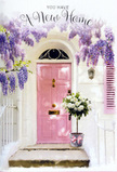The scene presents a sun-warmed doorway that seems tailor-made for celebrating a new home in Grove Park. At the centre, a pale pink front door glows softly, its colour delicate yet confident, framed by clean white walls that reflect the light back into the space. The overall effect is calm and uplifting, like the stillness you find on a quiet residential street a short walk from the Thames. Draped above and around the doorway, wisteria tumbles in loose, cascading strands of lavender and soft purple, each cluster of blossoms made up of tiny, graceful petals. The vines wind from somewhere above the frame, suggesting a seasoned pergola or balcony overflowing with spring growth. Light sifts through the wisteria, leaving dappled patterns of shade and brightness along the door, the wall, and a gently painted shutter, adding a sense of depth and gentle movement. At the threshold, resting firmly on the stone step, sits a grey metal bucket brimming with lush white and cream roses. The roses are fully open, their velvety petals layered densely to create a feeling of abundance and softness, while small tufts of fresh green foliage emerge here and there to give shape and contrast. Around the base of the bucket, a blush-pink ribbon is tied in an understated bow, subtly mirroring the door's hue and pulling the pastels together into a harmonious palette. You can almost sense the cool touch of metal, the soft brush of petals, and the faint perfume of wisteria and roses mingling in the afternoon air. The atmosphere is tender and quietly celebratory, perfectly capturing the joy and anticipation of moving into a new Grove Park home, and the heartfelt thought behind a floral arrangement left ready and waiting by the door.